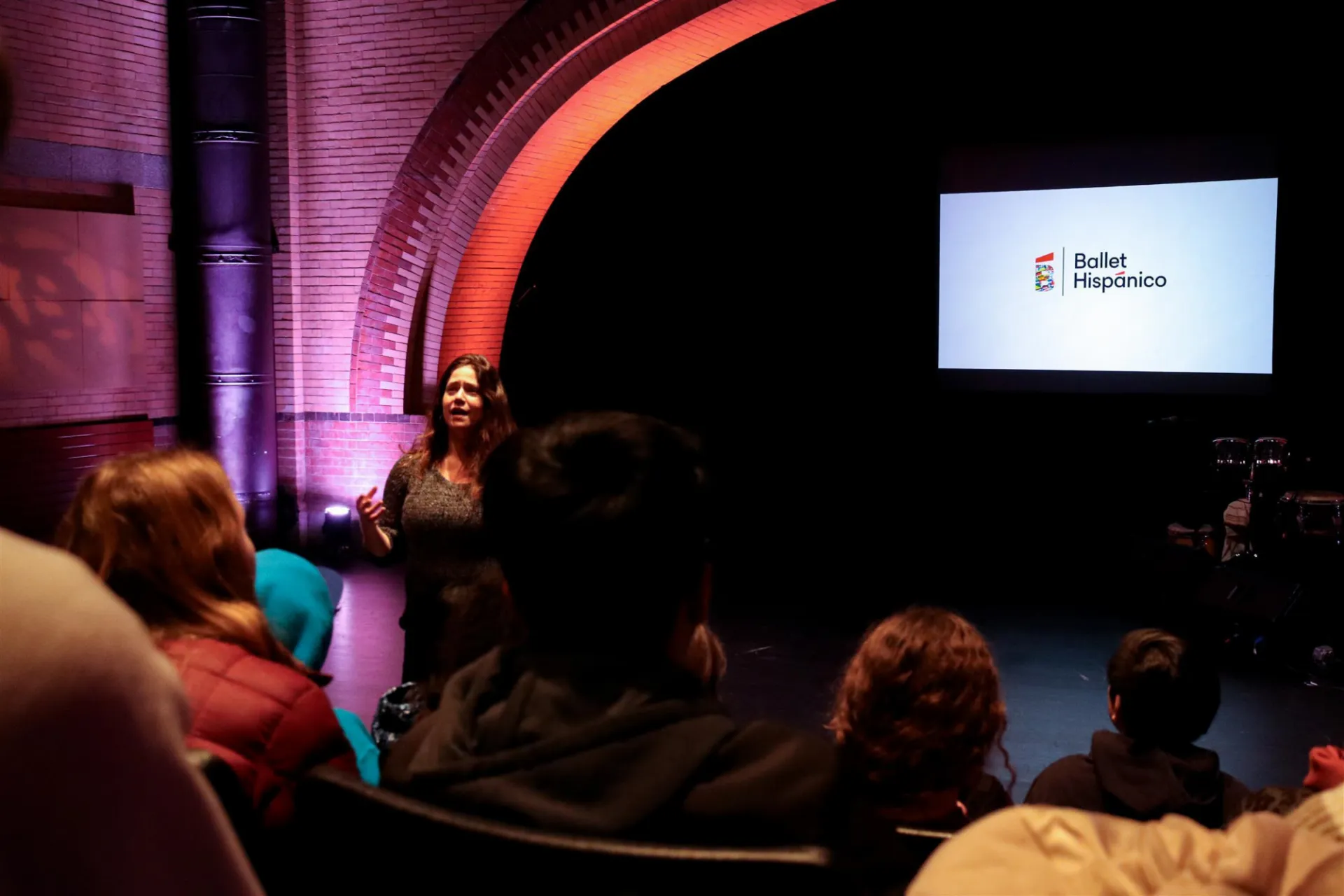 teacher addressing students in audience in Ballet Hispánico theater 