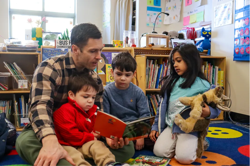 adult and students reading a book