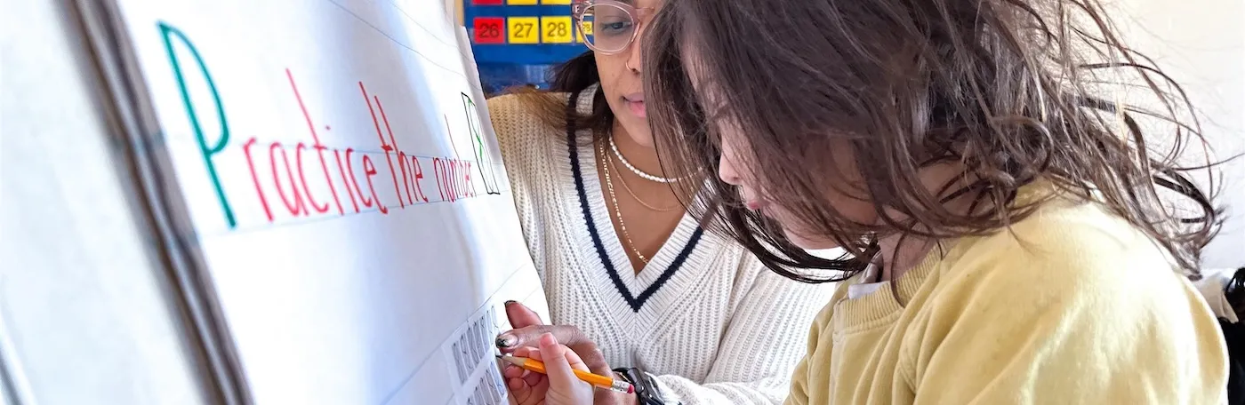 child and teacher writing on a board